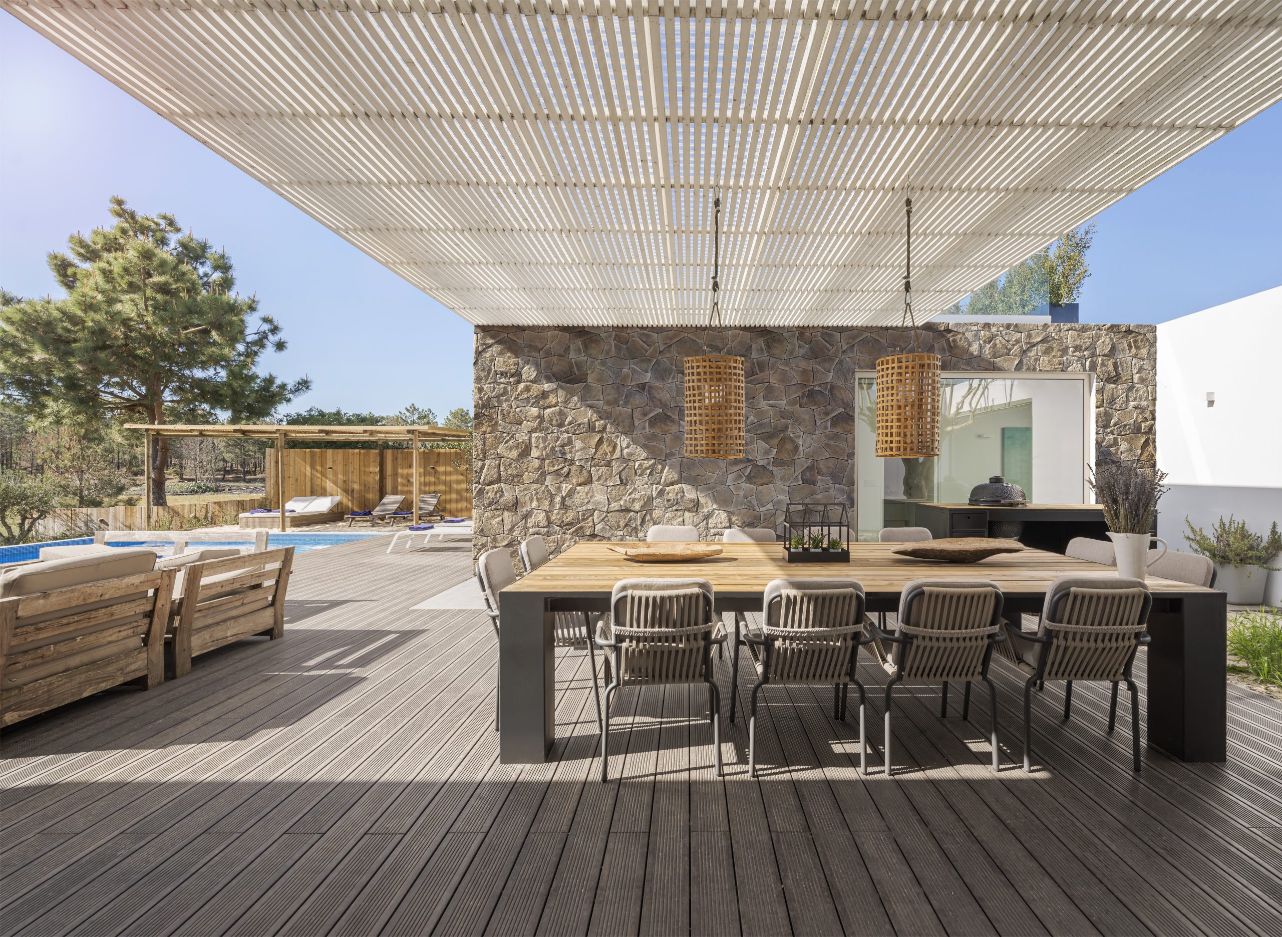 terrasse moderne avec piscine, grande table pour accueillir les invités, sol en bois, parement sur le mur Incerto ORSOL